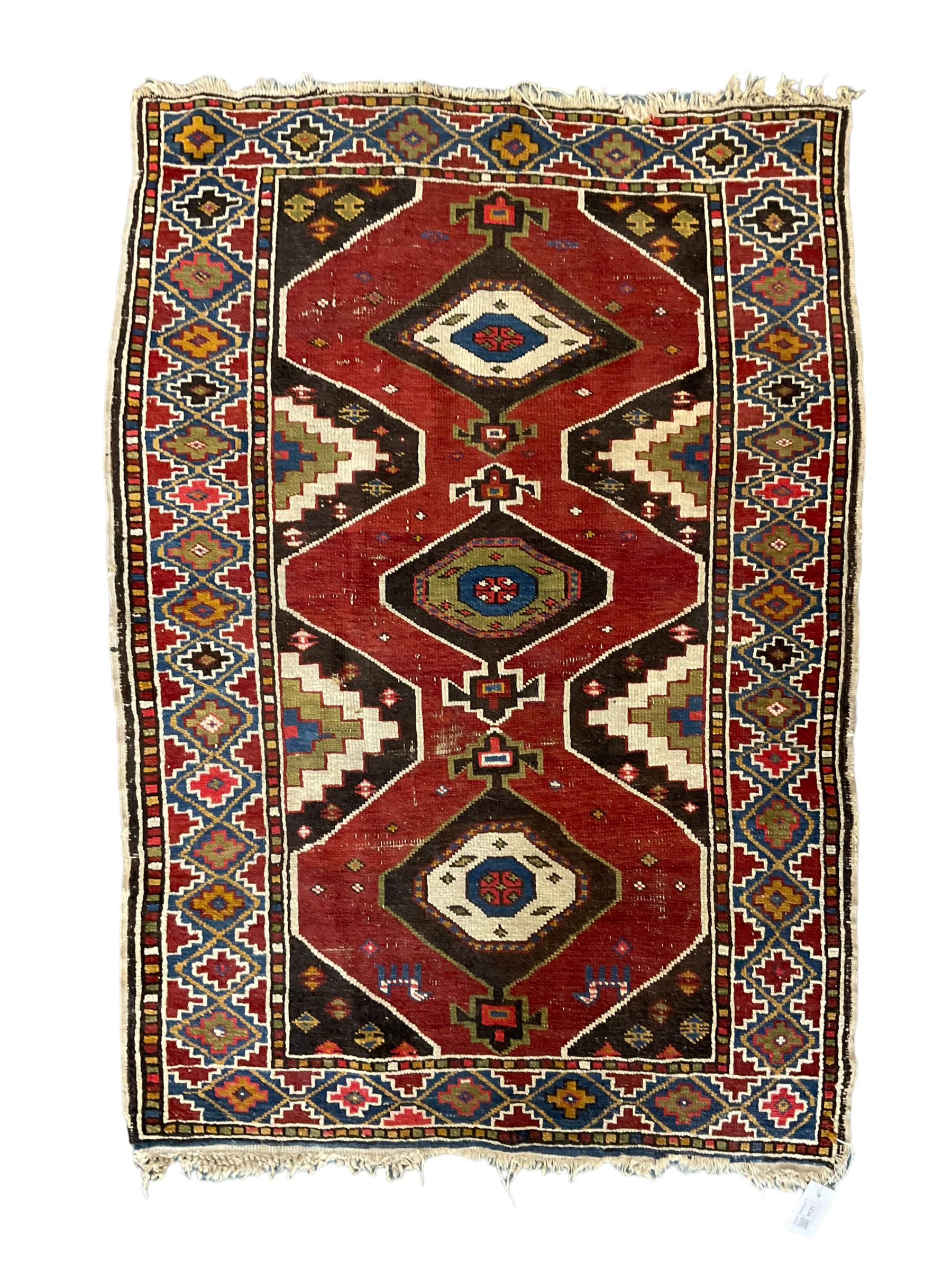 Anatolian Turkish red ground rug, decorated with three central lozenges, the multi-colour guarded border with repeating geometric shapes