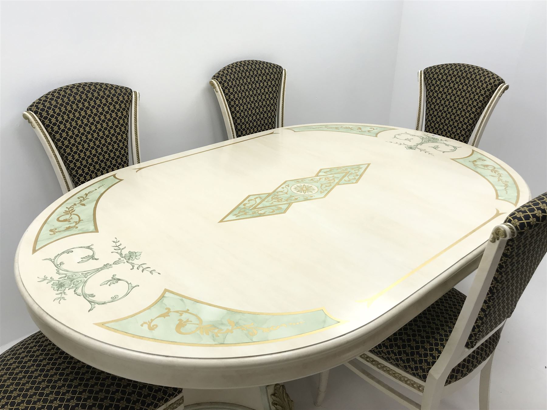 Italian style dining table, oval top with green marble finish spandrels, gilt scroll work and detail, central stepped lozenge motif, on two concaved square tapering pedestals with fluted uprights mounted with gilt acanthus scrolls (W198cm, H74cm, D130cm) and set five cream and gilt finished dining chairs, upholstered back and seat, turned tapering supports (W50cm)