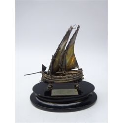  Silver scallop dish by Joseph Gloster Ltd, Birmingham, cased pair of French silver sugar tongs and small silver model of a boat with presentation plaque on ebonised oval plinth (3)  
