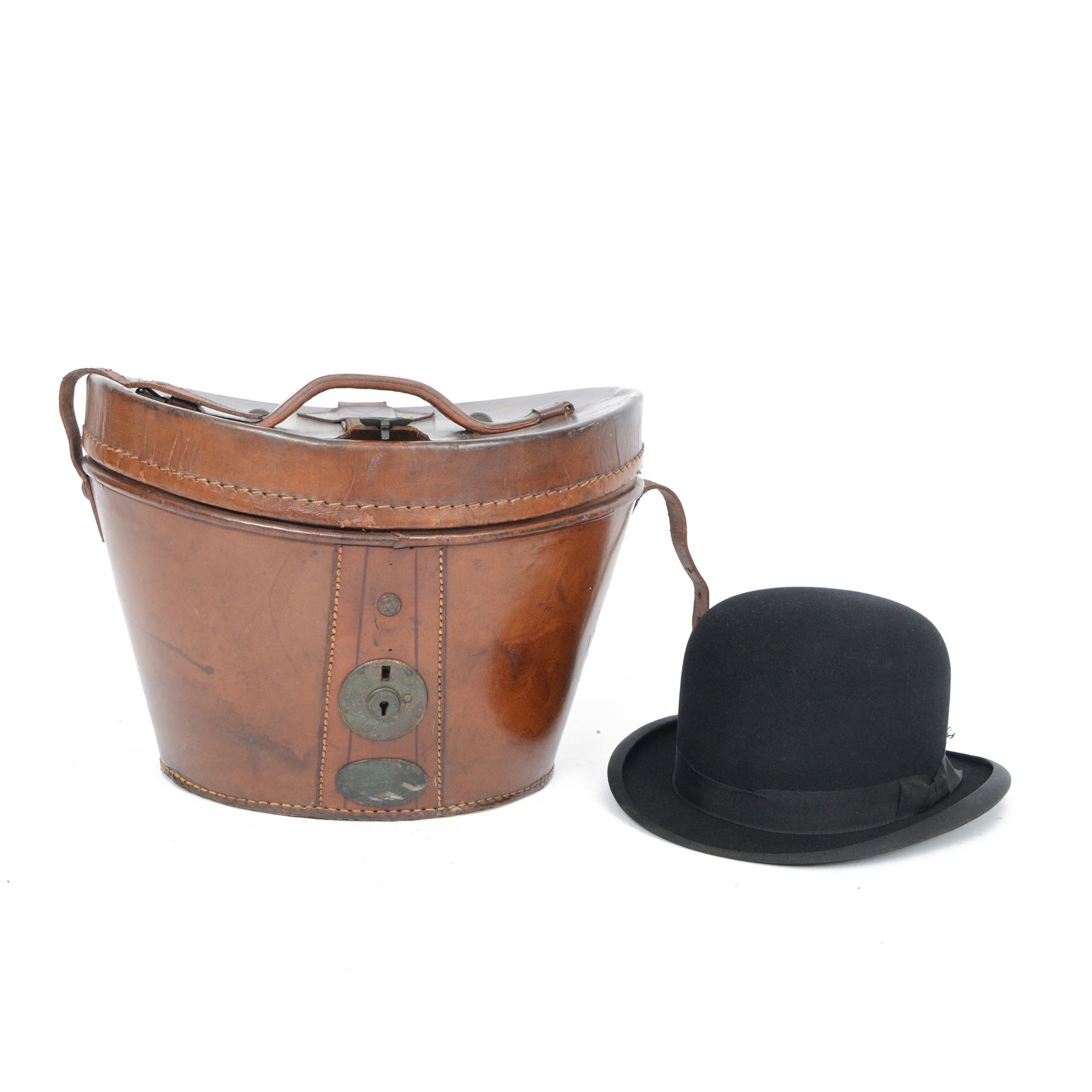 Bowler hat, by Moores, with retail label for Kendall of Scarborough, with brown leather top hat box having a handle to the lid and buckle fastening, lined in red velvet, marked W.B. to the front 