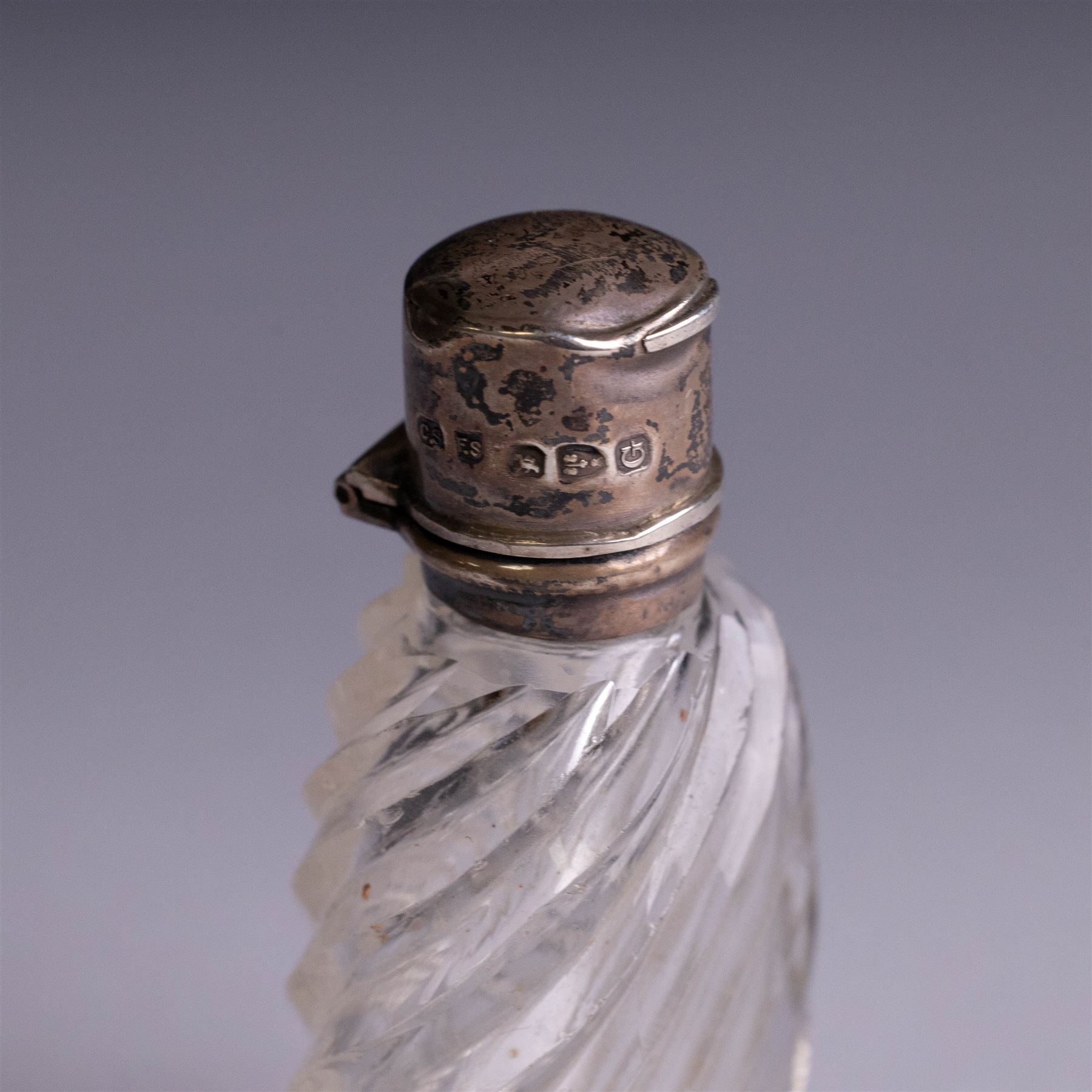 Three silver topped scent bottles, comprising cut glass example with pink guilloche enamel cover, oval example with blue guilloche enamel cover and one other, all hallmarked, largest H6.5cm