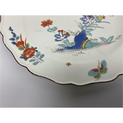 Mid 18th century Chelsea red anchor period plate, circa 1752-1754, hand painted in enamels in the Kakiemon palette with flowering peony and chrysanthemum issuing from rock work, and butterfly in flight above, the shaped rim detailed with conforming floral sprigs and butterflies within a iron red line border, with red anchor mark beneath, D22cm