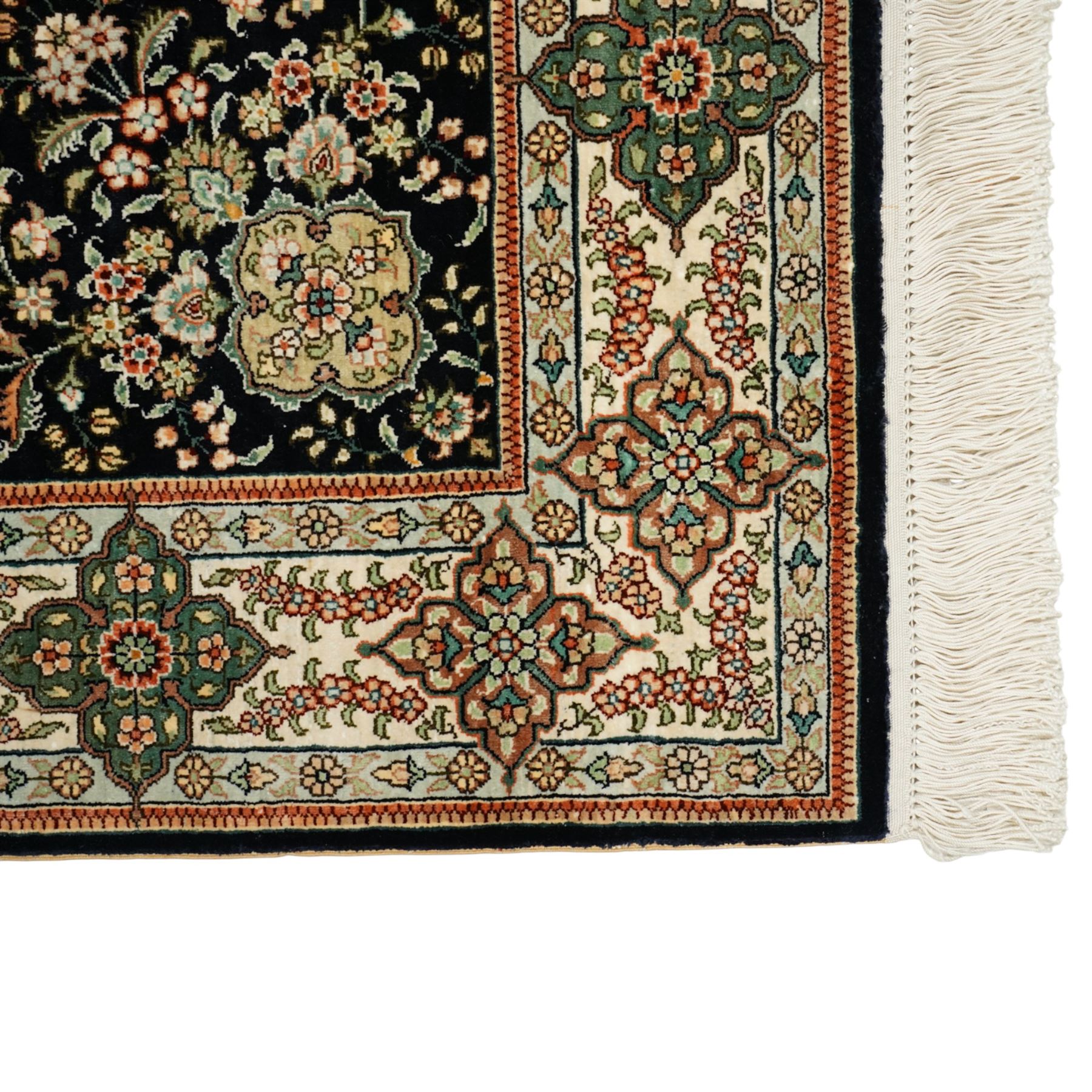 Persian-inspired Qom-style silk rug, deep indigo ground, profusely decorated with foliate motifs and a central medallion, with cotton fringe ends 