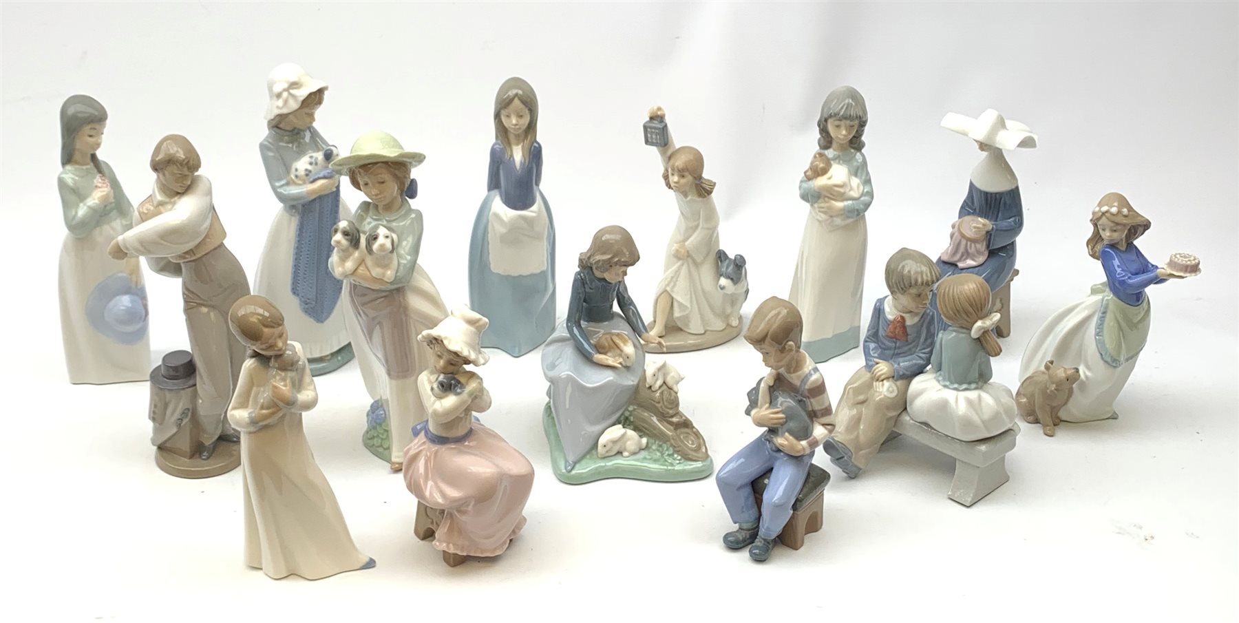 A group of thirteen Nao figurines, together with one Lladro figurine, each with printed mark beneath. 