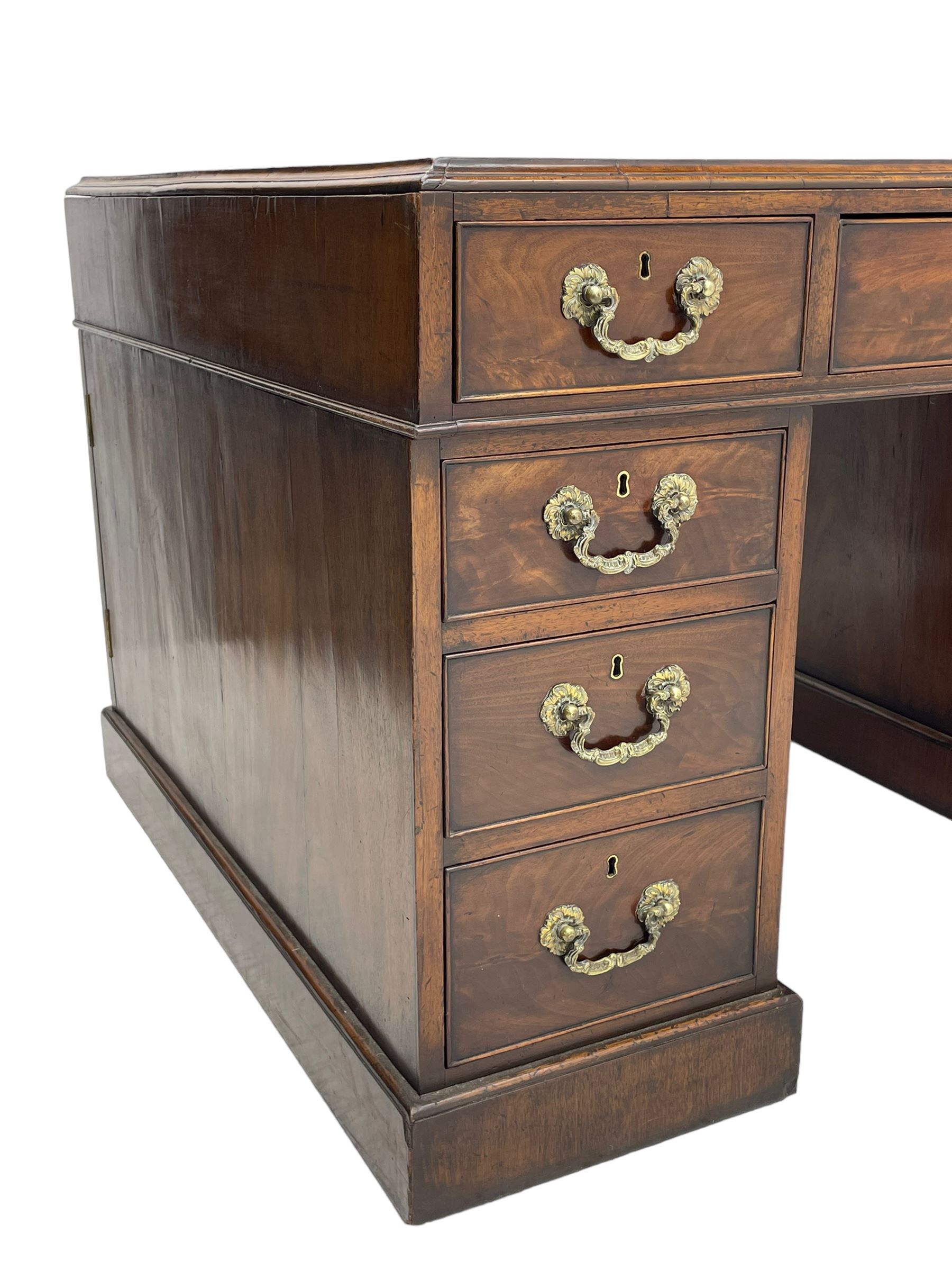 George III mahogany twin pedestal partner's desk, moulded rectangular caddy top with tooled leather inset, one side fitted with nine drawers and the opposing side fitted with single drawer, two false drawers and two panelled cupboards, ornate cast gilt metal handles and handle plates, on plinth base