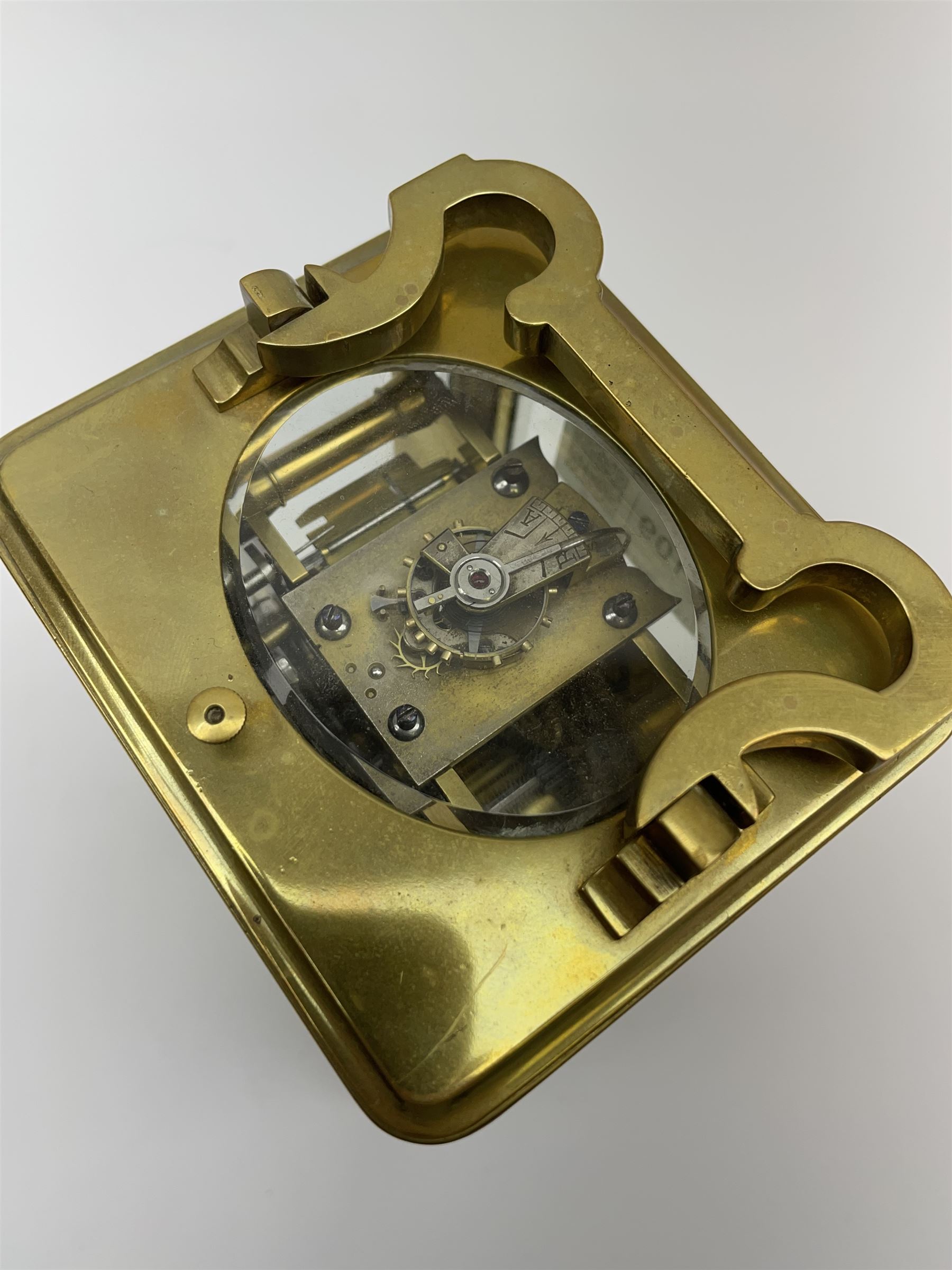 Early to mid 20th century French brass and bevelled glass cased carriage clock, the shaped loop handle over oval glass panel, white enamel Roman dial, twin train driven eight day movement striking on coil, with button push repeater, the movement back plate stamped for 'R & Co.'