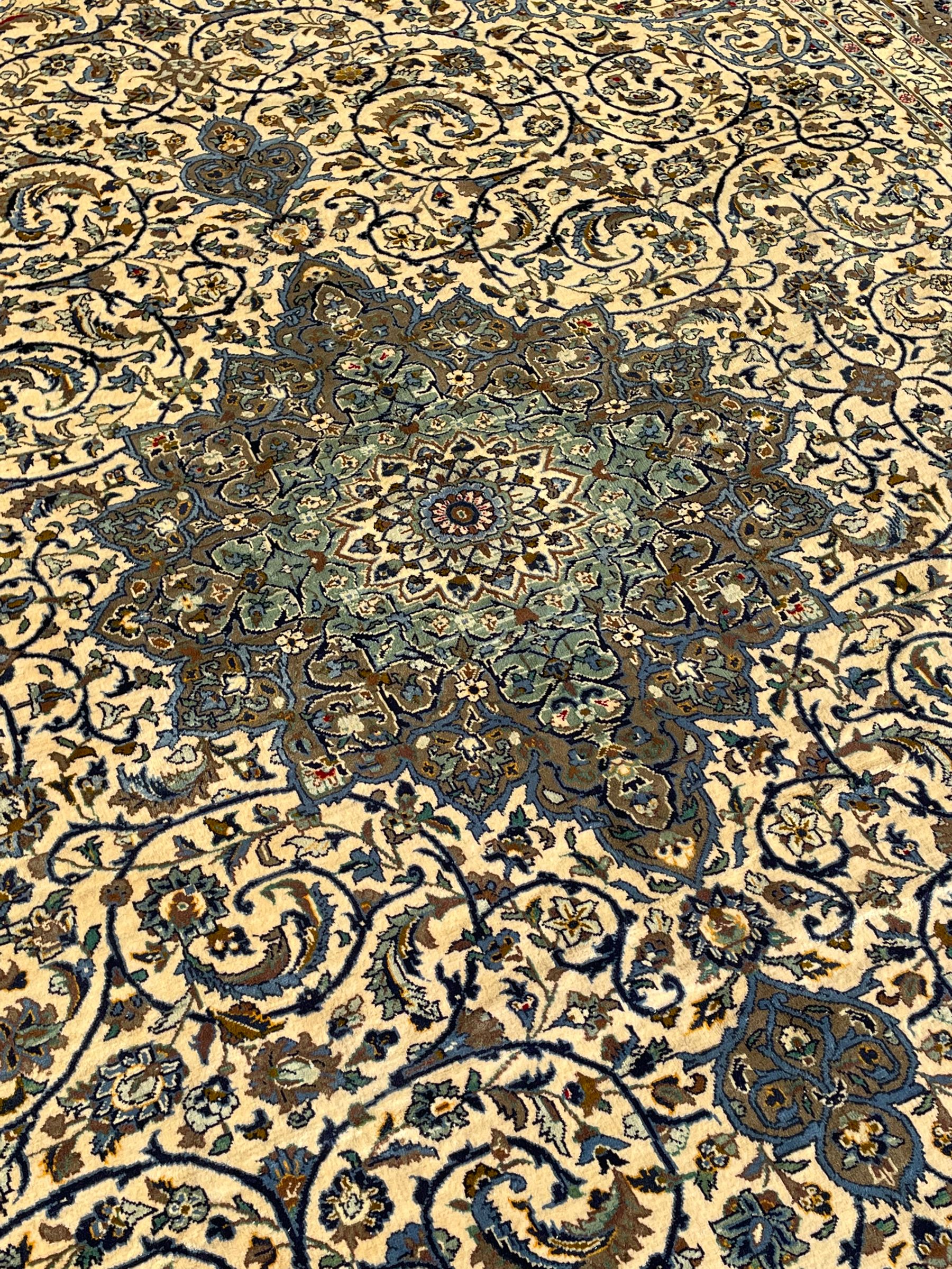 Persian Meshed carpet, ivory ground and decorated with intricate floral design with trailing scrolled branch, the central medallion decorated with stylised plant motifs, seven band border, the main band decorated with scrolls and flower head motifs