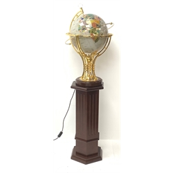 An electric operating rotating gem stone style globe with brass mount and wooden base, upon wooden hexagonal column stand. 