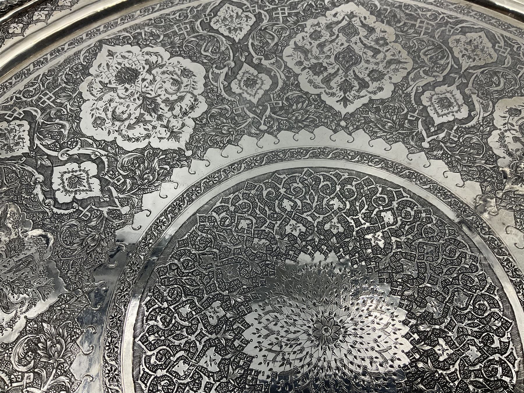 Early/mid 20th century Persian silver tea service, comprising circular serving tray, teapot, twin handled sucrier and cover, milk jug, five tea glasses with six silver holders, six tea spoons, and pair of sugar tongs, each profusely chased with foliate arabesque decoration, each bearing marks including 84 for 840 fineness, tray D40cm, teapot H16cm