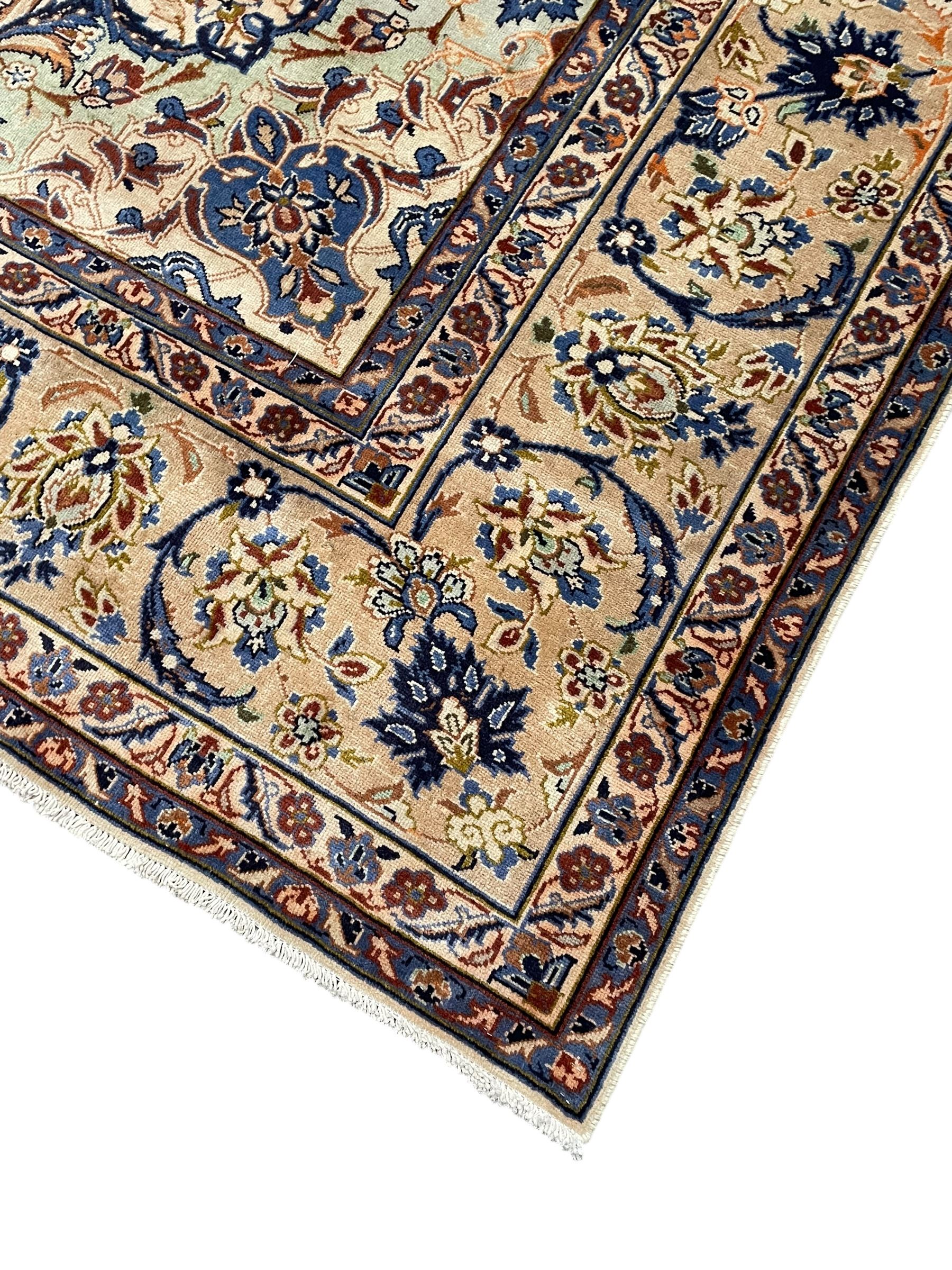 Persian Kashan ivory ground carpet, floral design central medallion surrounded by trailing and interlaced leafy branches with palmettes and flower heads, matching patterned border with guard stripes 