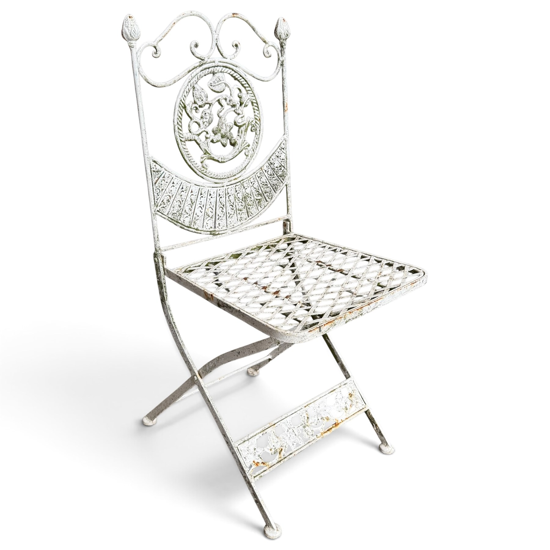 Three-piece French style white-painted wrought iron garden bistro set, comprising a circular folding table with latticework top and apron with scrolling foliate motifs (W70cm H80cm) and matching pair of chairs, with scrolling cresting rail and acorn finials over a scrolled foliate medallion, raised on lattice seat and folding X-frame base (W42cm H93cm)