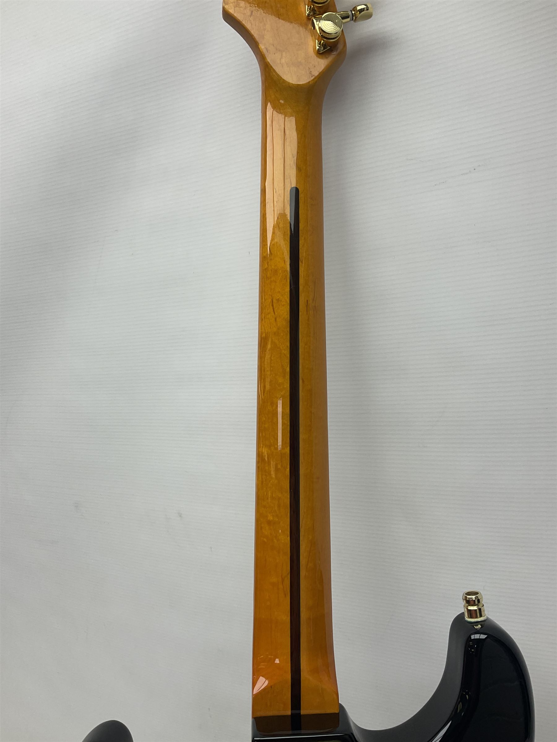 Copy of a Fender Stratocaster electric guitar in black with Wilkinson bridge, lock-in tuners, synchronised tremolo and various patent numbers; L99cm; in hard carrying case with strap and digital tuner