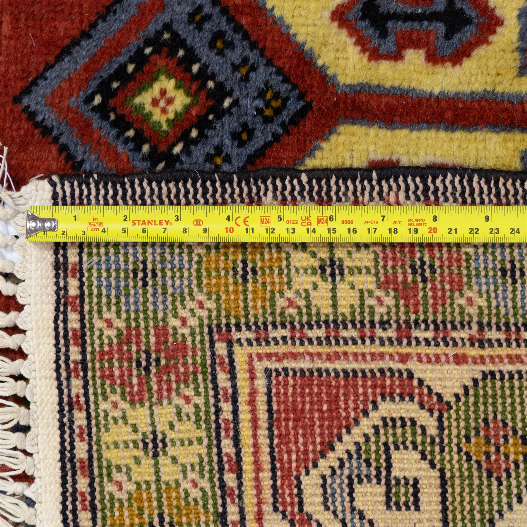 Caucasian Kazak design wool rug, cream field with three large geometric medallions and stylised hooked motifs, enclosed by polychrome reciprocal border and green floral guard stripes
