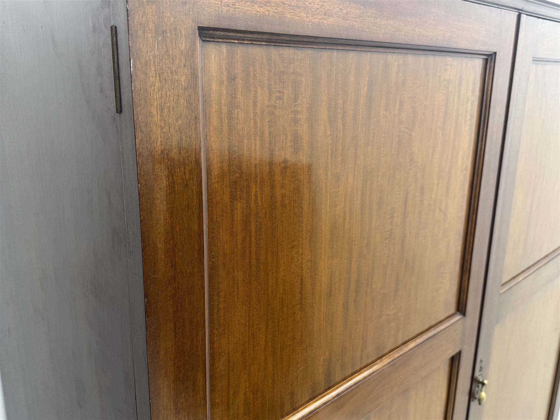 Wylie & Lochhead, Glasgow - early 20th century mahogany and satinwood double wardrobe, projecting cornice over panelled doors, interior fitted with mirrored door, shelves, drawers, hooks and hanging rail, raised on bracket supports with ceramic castors