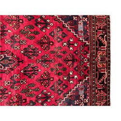 Persian Joshaghan crimson ground rug, stepped lozenge medallion surrounded by repeating foliate lozenge motifs, the border decorated with stylised plant motifs, within geometric guard stripes 