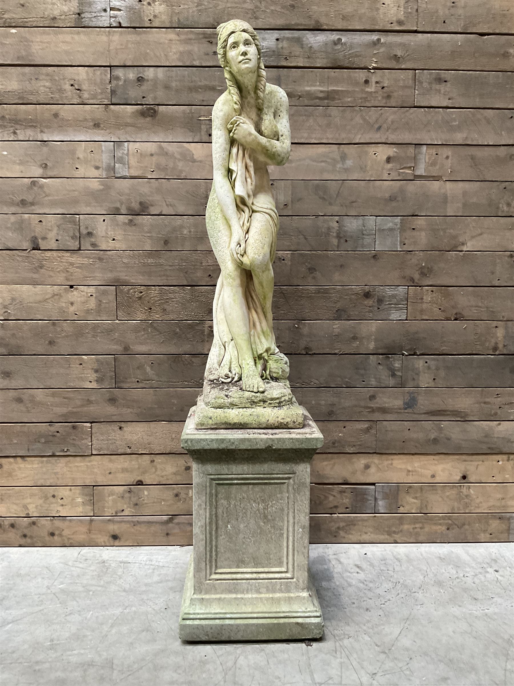 Cast stone garden figure of a bathing lady, raised on square plinth