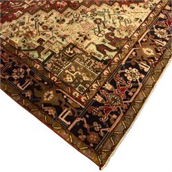 Northwestern Persian Heriz carpet, crimson ground and soft green field, with bold terracotta stepped medallion with angular spandrels and geometric motifs within a broad palmette and vine border 