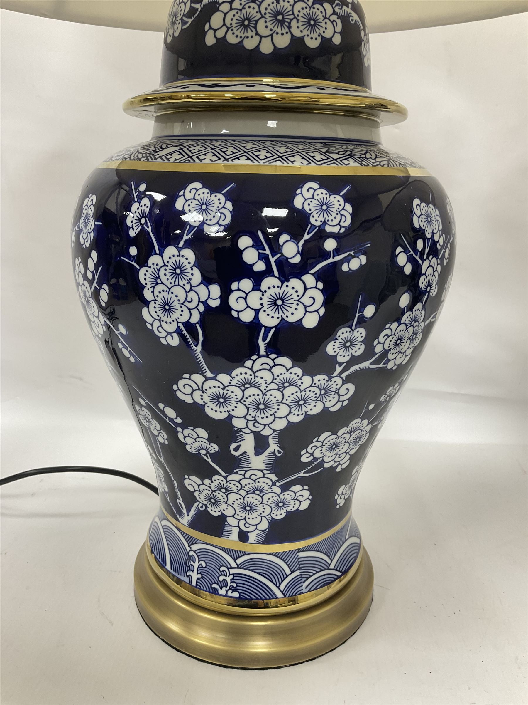 Pair of blue and white table lamps, each of baluster form, decorated with prunus blossom, within stylised borders, raised upon circular gilt base, excluding fittings H48cm