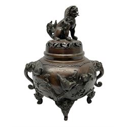 Japanese bronzed koro, the body of globular form with twin cast zoomorphic mask handles, decorated in relief with birds upon blossoming branches, against a ground incised with rushes and peonies, the flat toped domed cover with pierced band and surmounted by a cast figure of a Foo dog, the whole upon three zoomorphic mask feet, with impressed character type mark beneath, H35.5cm