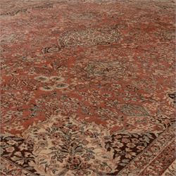 Persian vermillion ground Kashan rug, the busy field decorated with a central floral pole medallion, surrounded by trailing foliage and profusely woven floral patterns and bouquets, the dark indigo spandrels and multiple guard bands with similar floral decoration and stylised spandrels