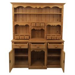 20th century country style waxed pine housekeeper’s cupboard, upper section with moulded cornice, shaped aprons and open shelving around central drawer arrangement, the lower section fitted with three drawers and two cupboards with panelled doors, raised on a plinth base