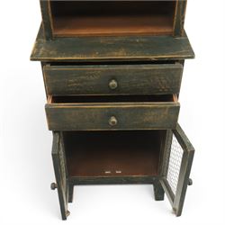20th century pine kitchen cabinet in a green painted finish, top section with upper door with wire front above a recessed shelved area, the lower section with two drawers and twin wire fronted doors, raised on tapered supports
