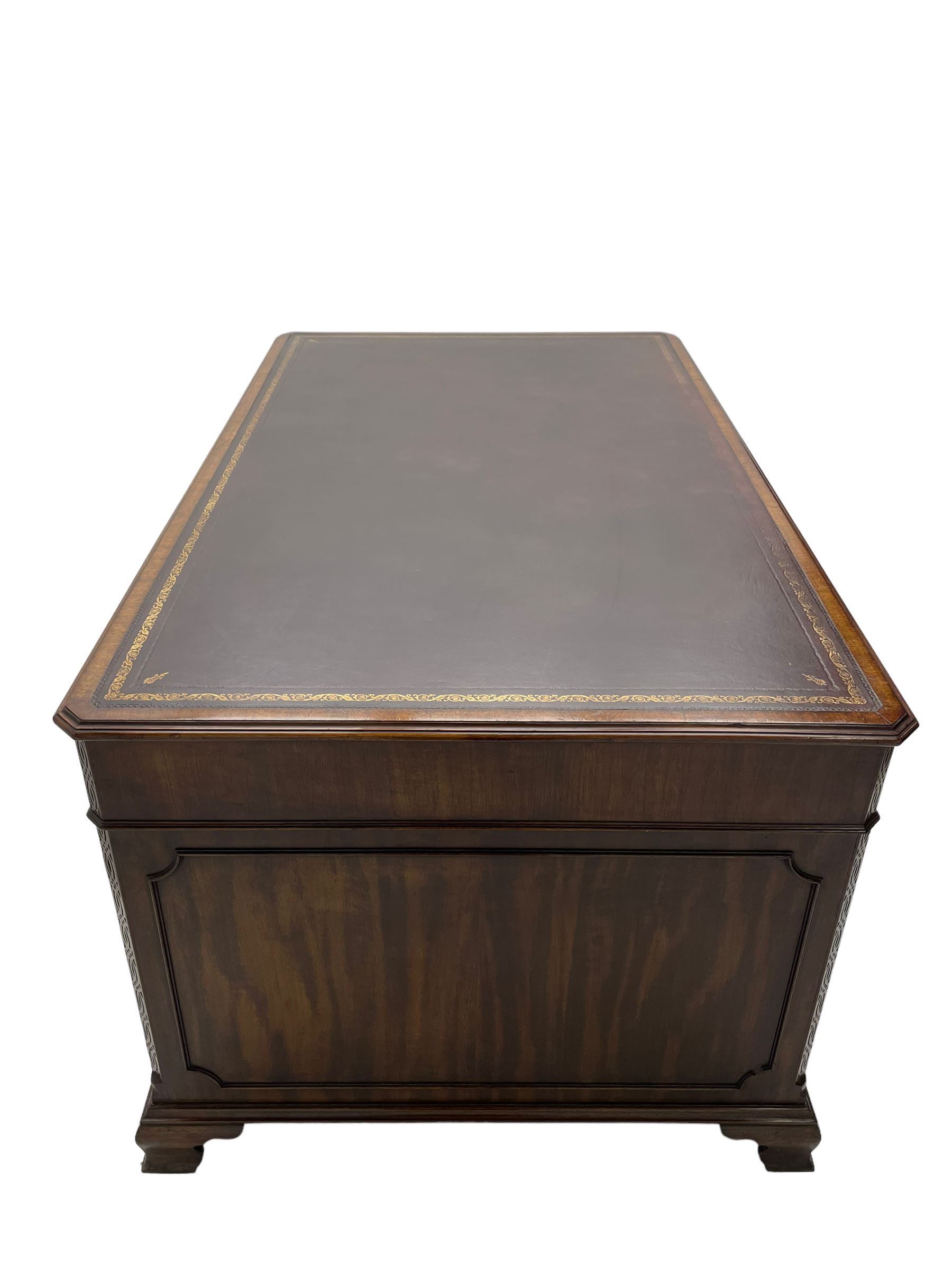 Large Georgian design mahogany twin pedestal partner's desk, moulded rectangular top with canted corners and inset leather writing surface, fitted with nine drawers and two cupboards, the pedestals with canted uprights decorated with blind fretwork, on ogee bracket feet
