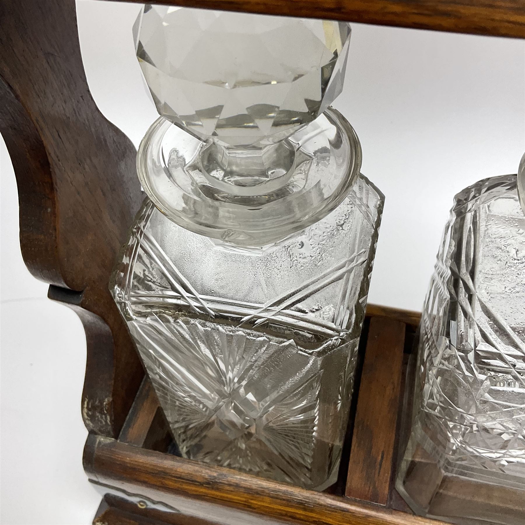 A Mappin & Webb silver plate mounted oak tantalus, containing three square sided cut glass decanters, complete with key, H35cm, together with a further square sided decanter. 