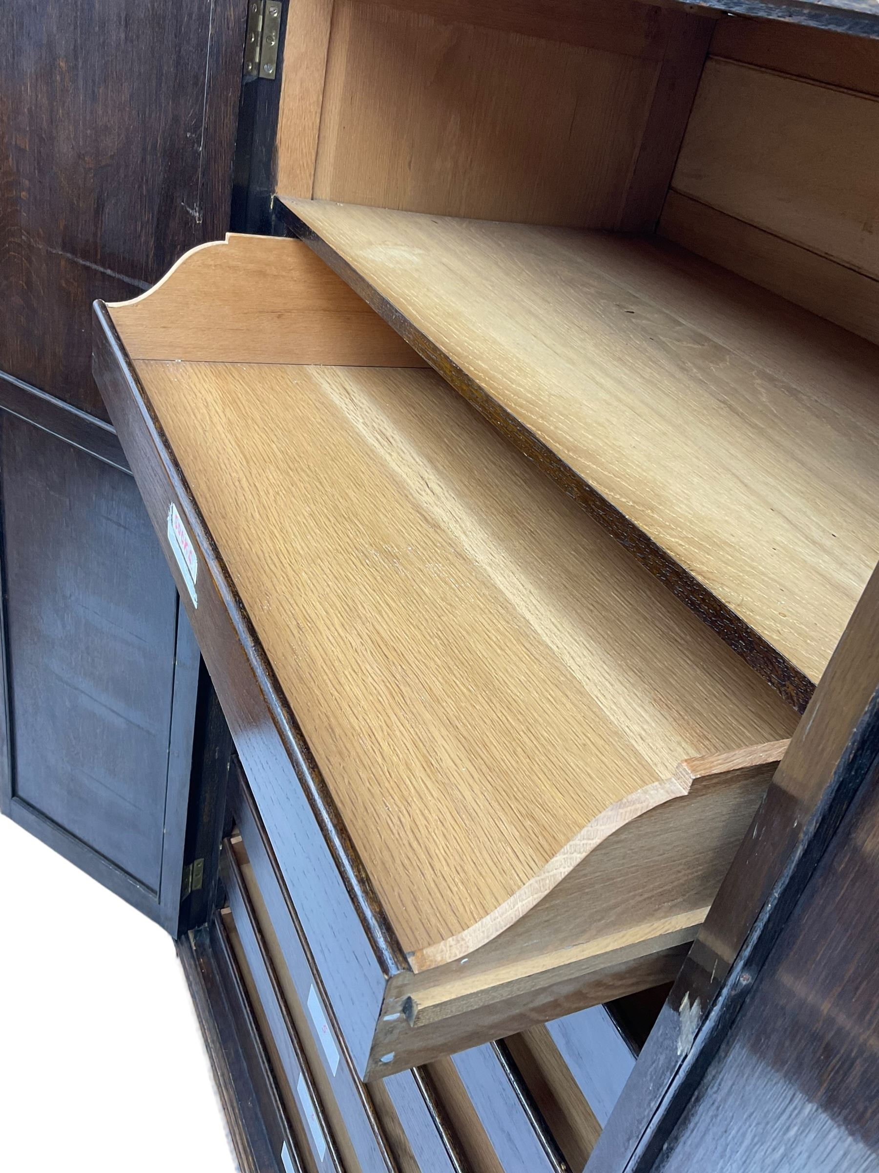 Early 20th century oak triple wardrobe, three panelled doors with geometric mouldings and fretwork spandrels, the interior fitted with slides and hanging rail