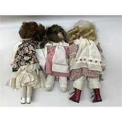 Three porcelain headed dolls, with inset glass dressed in traditional clothing with lace detail and wigs