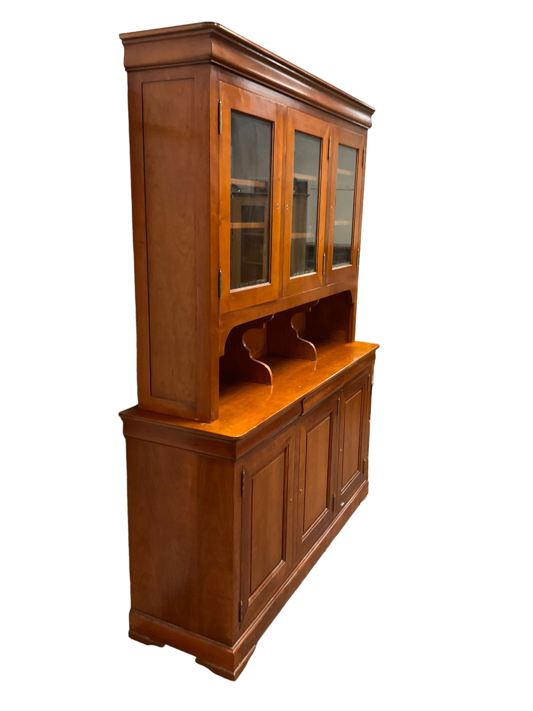 Multi-York -  Loire cherry wood dresser, shaped cornice over three glazed doors enclosing six shelves, the lower section fitted with three shallow drawers with shaped fronts over three cupboards with panelled doors, raised on plinth base with bracket feet