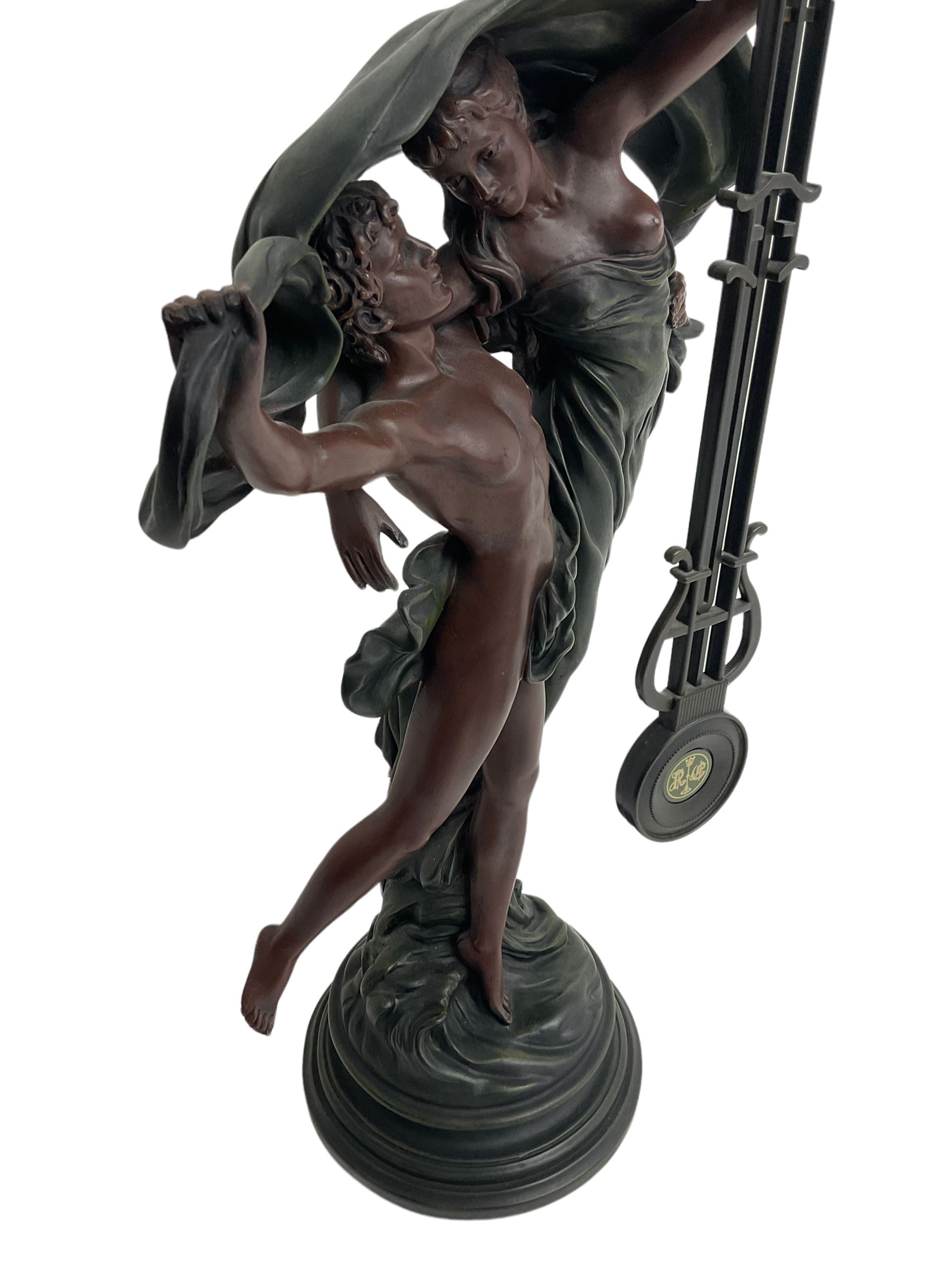 Decorative contemporary “Mystery Clock” with battery operated quartz movement, movement supported by two figures in a classical pose on a circular base, dial inscribed “Juliana”.