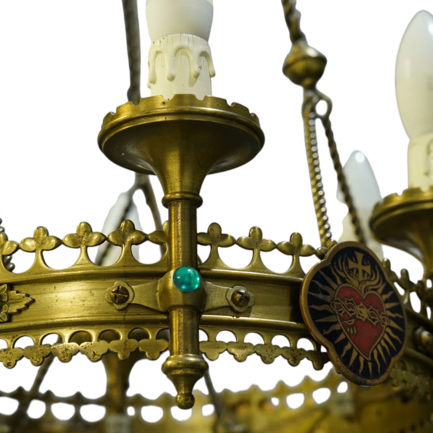Gothic Revival brass six-light ecclesiastical chandelier, circular frame with pierced trefoil cresting and apron, applied with polychrome Sacred Heart medallions, six candle-form electric sconces, suspended on twisted brass rods and chains from a coronet-form ceiling boss