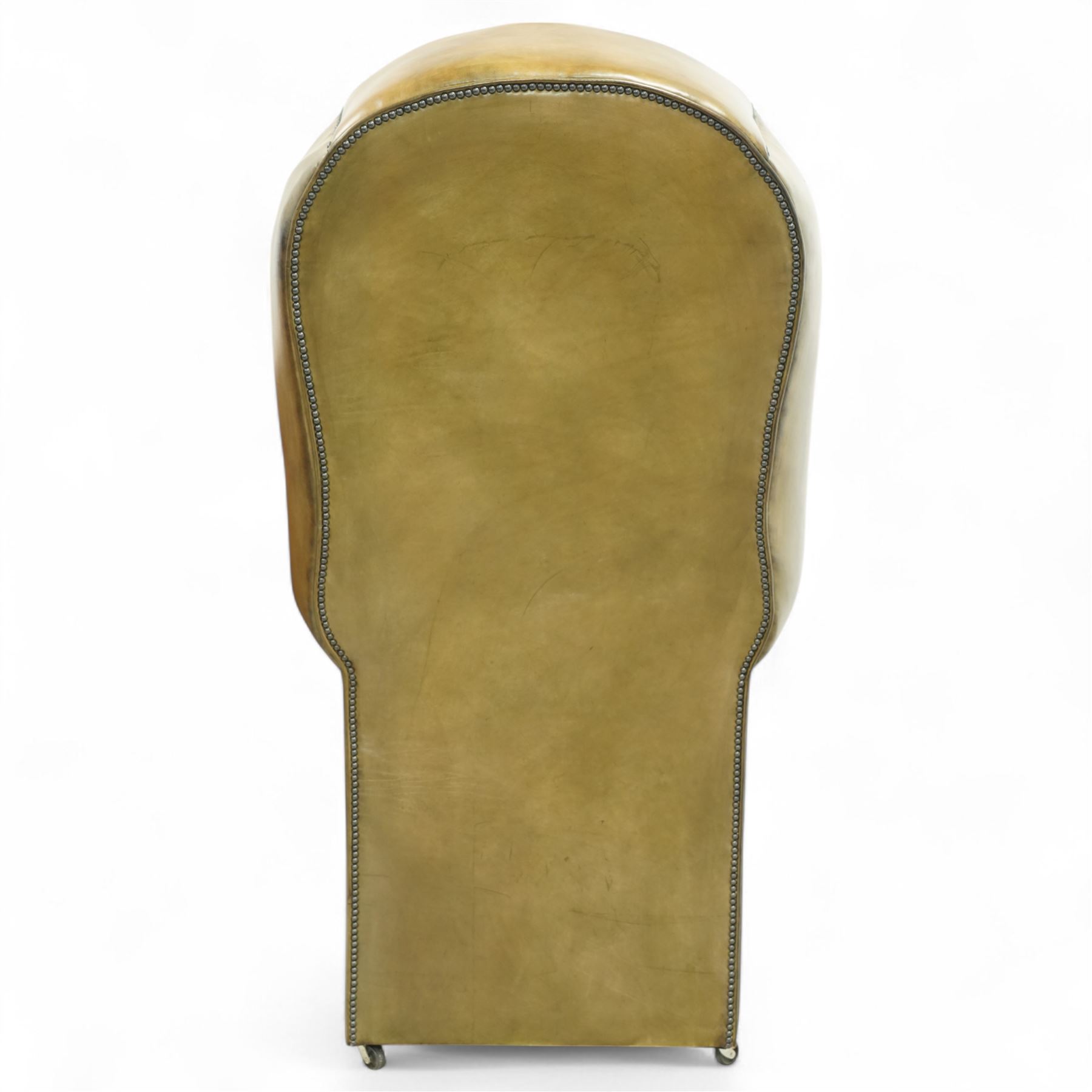 20th century George II style leather upholstered hall porters chair, brass studded upholstered with piping in leather on all sides, the inside top back arms and seat are all pleated and deep buttoned, with removable seat pad, on castors