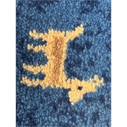Contemporary 'Royal Garden' wool pile rug, central cream field with a smaller red rectangular panel containing scattered animal and geometric motifs, bordered by a wide indigo band decorated with stylised figures, animals, and tree motifs