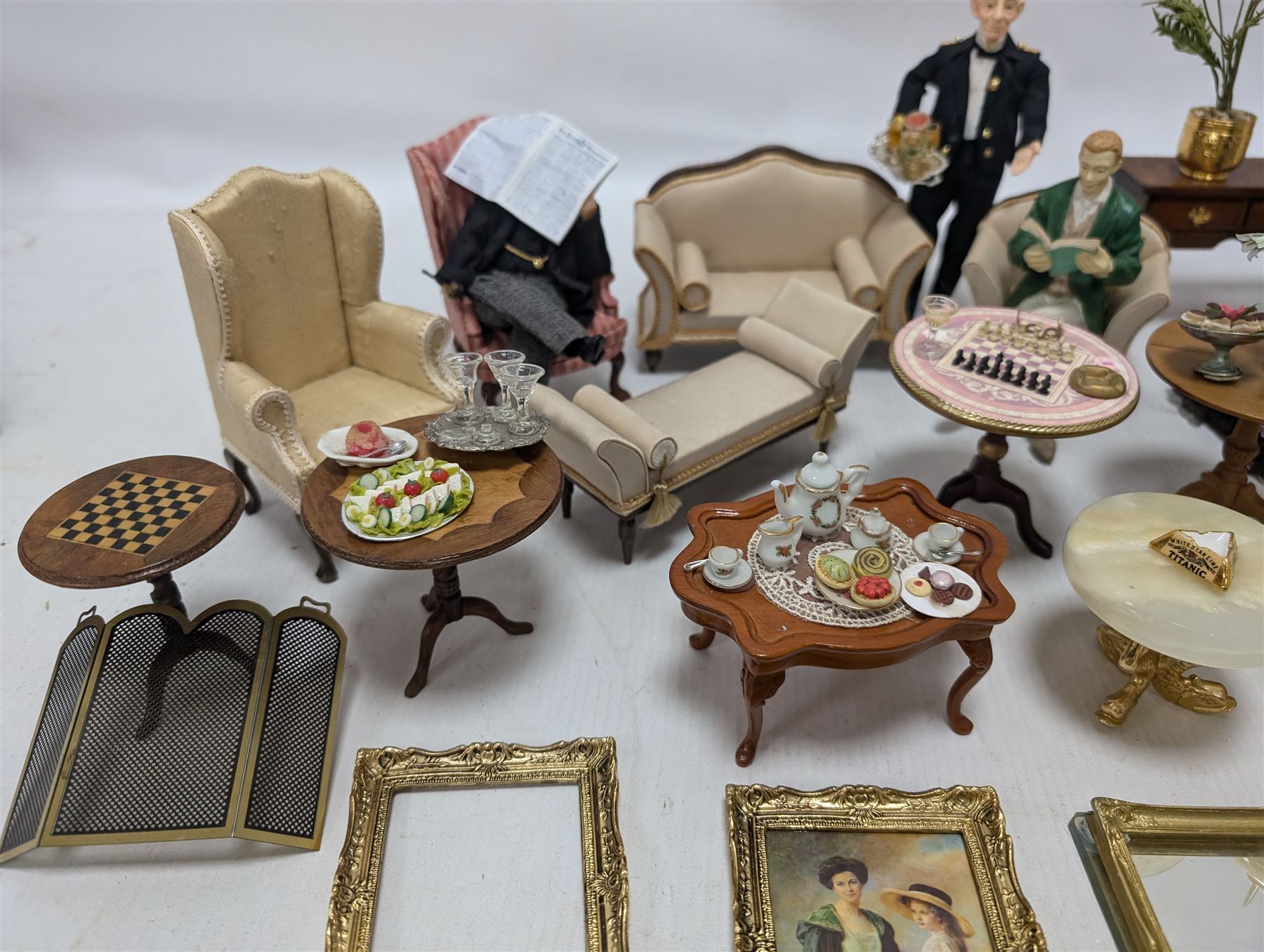 Dolls house furniture, including sofa, chairs, foot stools, fireplace, sideboards, five figures, mirrors, paintings and accessories