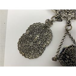 19th century continental silver plated chatelaine, the main body flanked with winged mythical beasts and central soldier slaying a dragon supporting three suspended items to include velvet lined small basket and long clasped filigree chain, together with a thimble