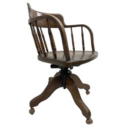 Early 20th century oak framed swivel Captain's chair, tub shaped back with turned spindle supports over saddle shaped seat, quadriform base on castors