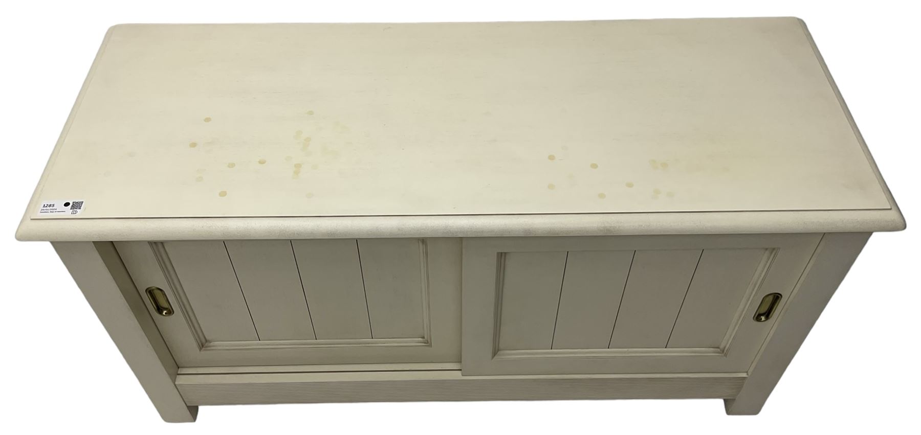 Cream finish low side cabinet, moulded rectangular top over two sliding panelled doors, on stile supports 