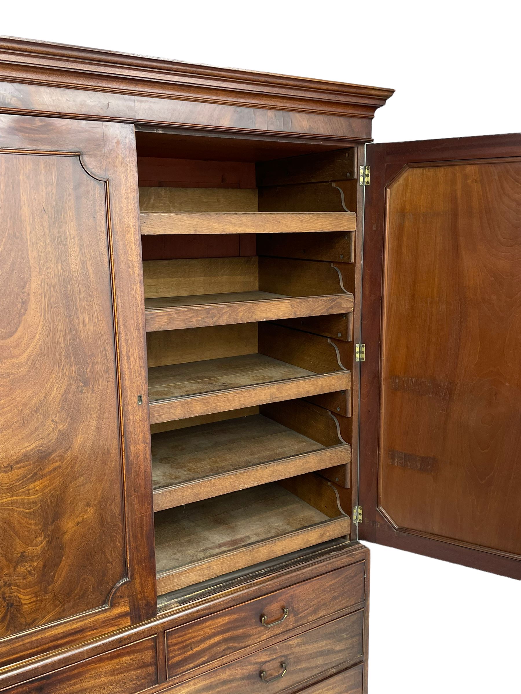 George III mahogany linen press, projecting cornice over two figured doors enclosing five linen slides, the lower section fitted with two short and two long drawers, on bracket feet