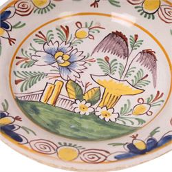 18th century Delft polychrome charger, decorated with a central landscape within a stylised floral boarder, D24cm 