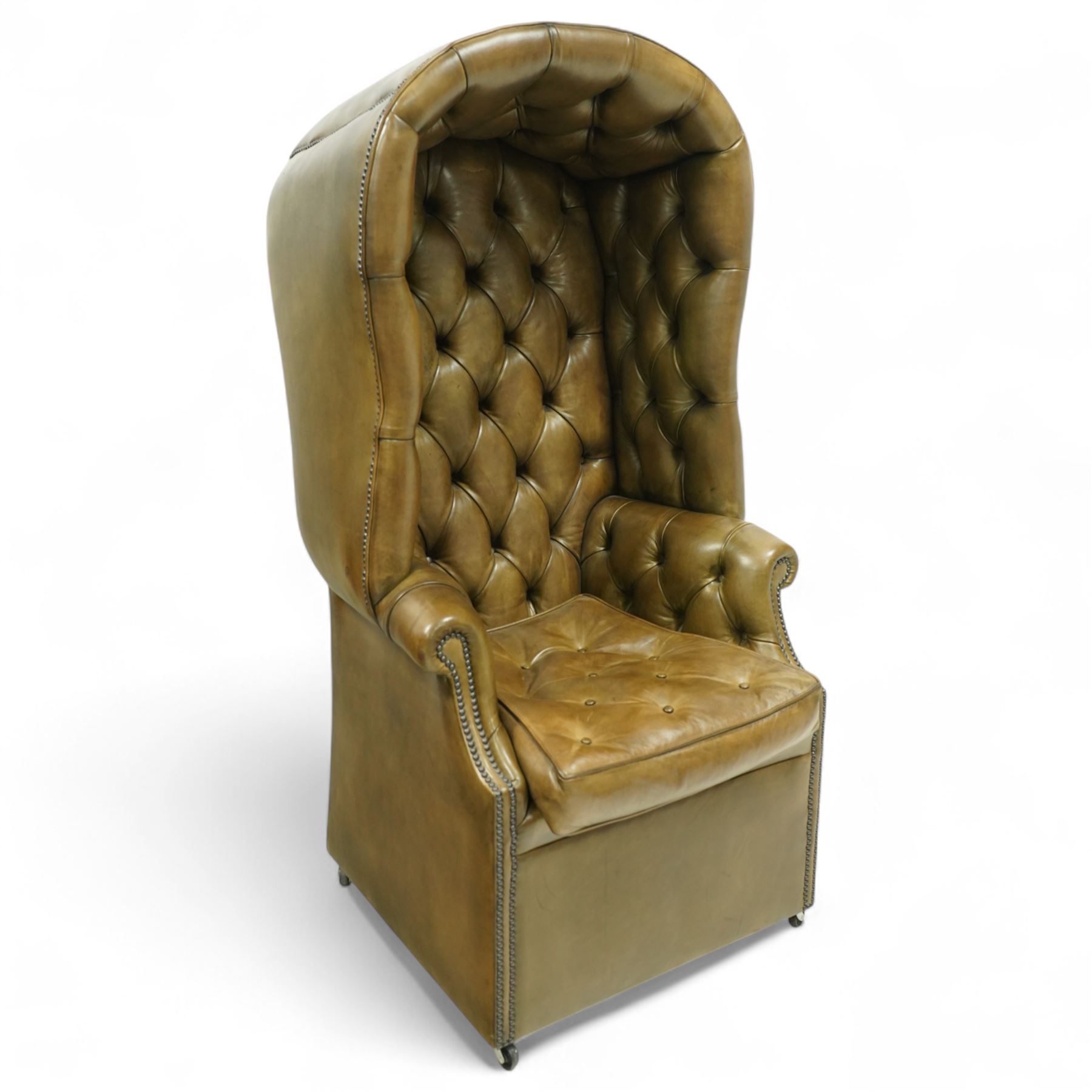 20th century George II style leather upholstered hall porters chair, brass studded upholstered with piping in leather on all sides, the inside top back arms and seat are all pleated and deep buttoned, with removable seat pad, on castors