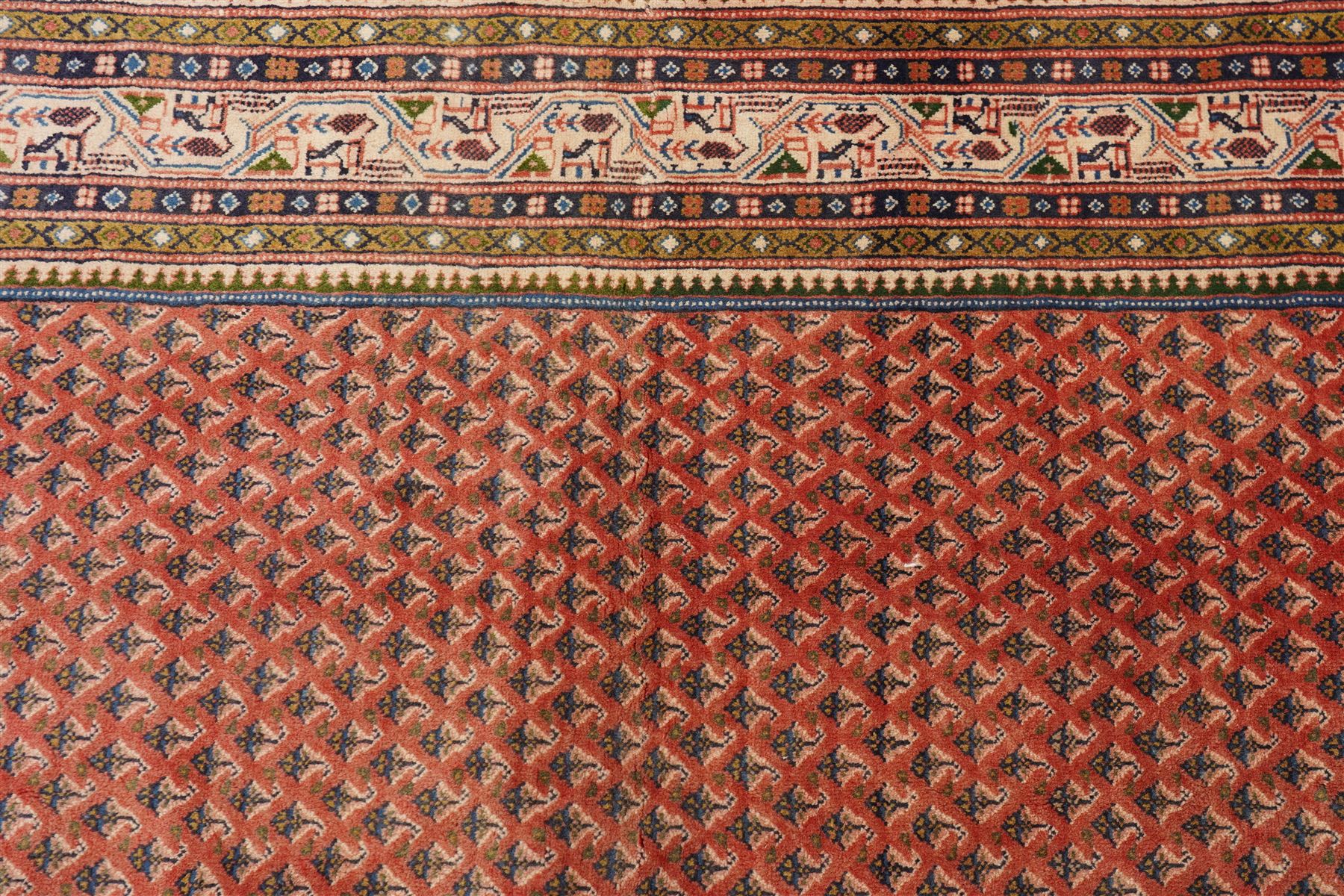 West Persian Boteh-Mir hand-knotted rug, madder red field densely decorated with a repeating lattice of of small boteh motifs arranged in diagonal rows enclosed by a broad border of stylized geometric devices and angular floral ornament between multiple guard stripes with cotton fringe ends