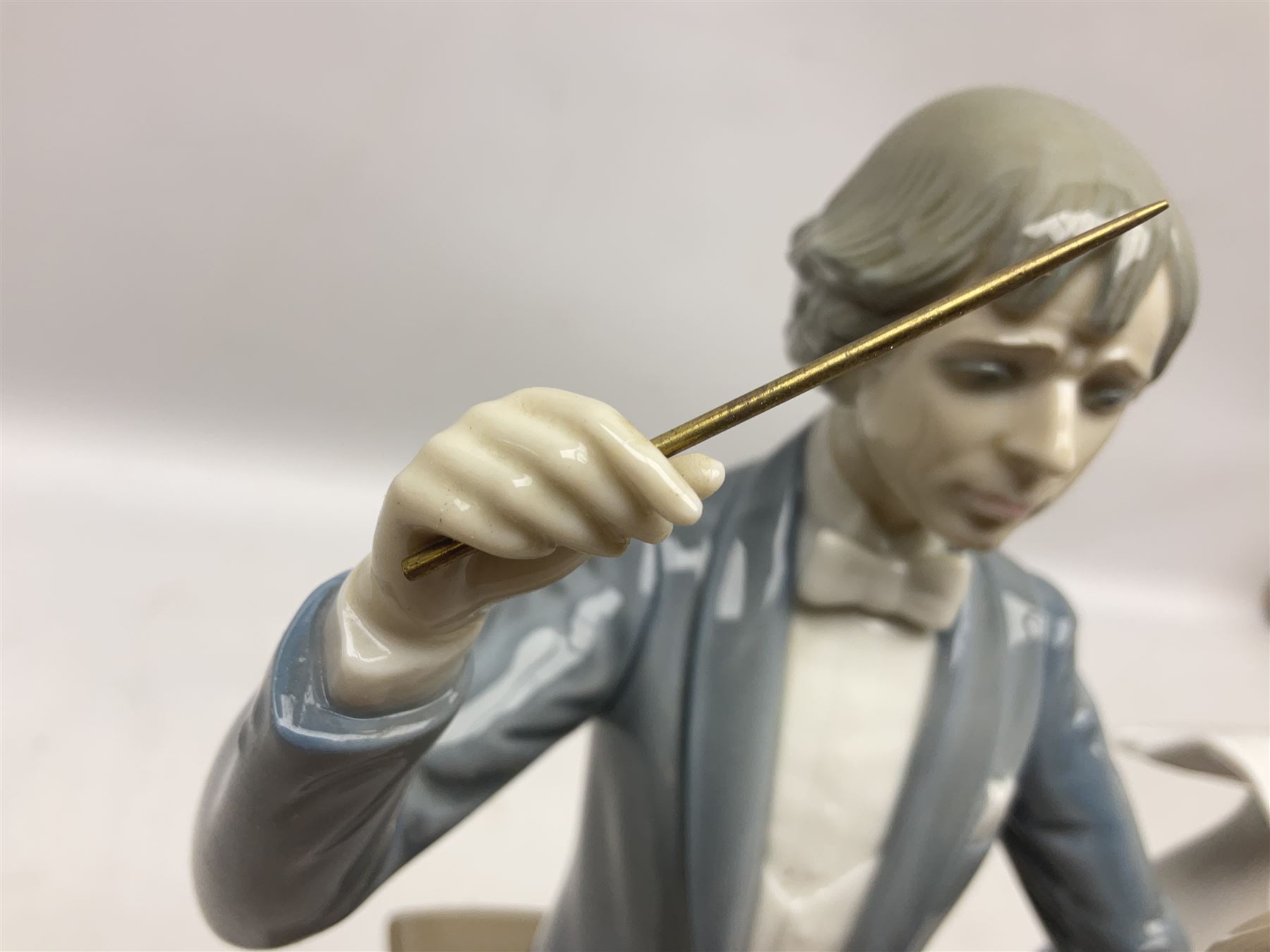 Two Lladro figures, comprising Conductor no 5196 and Prayerful Moment no 5500 together with a Lladro plaque and two Lladro candle holders, Dolphins at Play no 17666 and Sailing the Seas no 17665, all with original boxes, largest example H33cm 