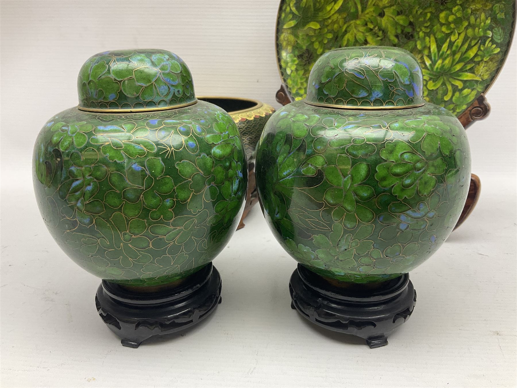 Pair of modern cloisonne ginger jars having floral decoration with a green ground, with hardwood stands, together with a similar plate and a bowl decorated with birds and flowers  