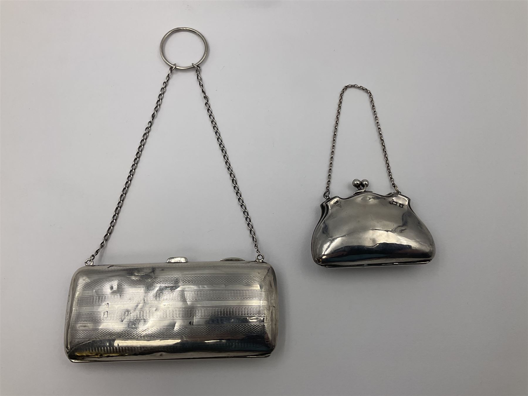 Early 20th century silver mounted coin purse, with leather interior and finger chain, hallmarked Samuel M Levi, Birmingham 1917, together with a similar Edwardian example, with engraved initials and engine turned decoration, hallmarked Birmingham 1907, maker's mark worn and indistinct, largest W11.3cm