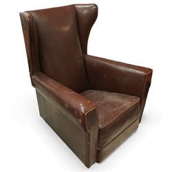 Early to mid 20th century pair of wingback armchairs, upholstered throughout in chocolate brown leather, the backs with deep wings, square padded arms with piped seams, loose seat cushions over solid bases
