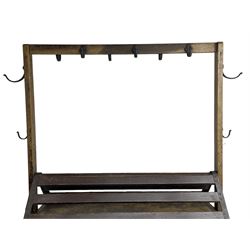 Cottam & Company, Winsley St. London - 19th century oak and metal framed tack and saddling trolley-stand, raised and collapsible frame fitted with wrought metal hooks, pointed and slated top over panelled sides, fall front cupboard to each side, on wrought metal frame with under tier, fitted with hinged handles and wheels, the frame inscribed 'Cottam & Company, Winsley St. London'