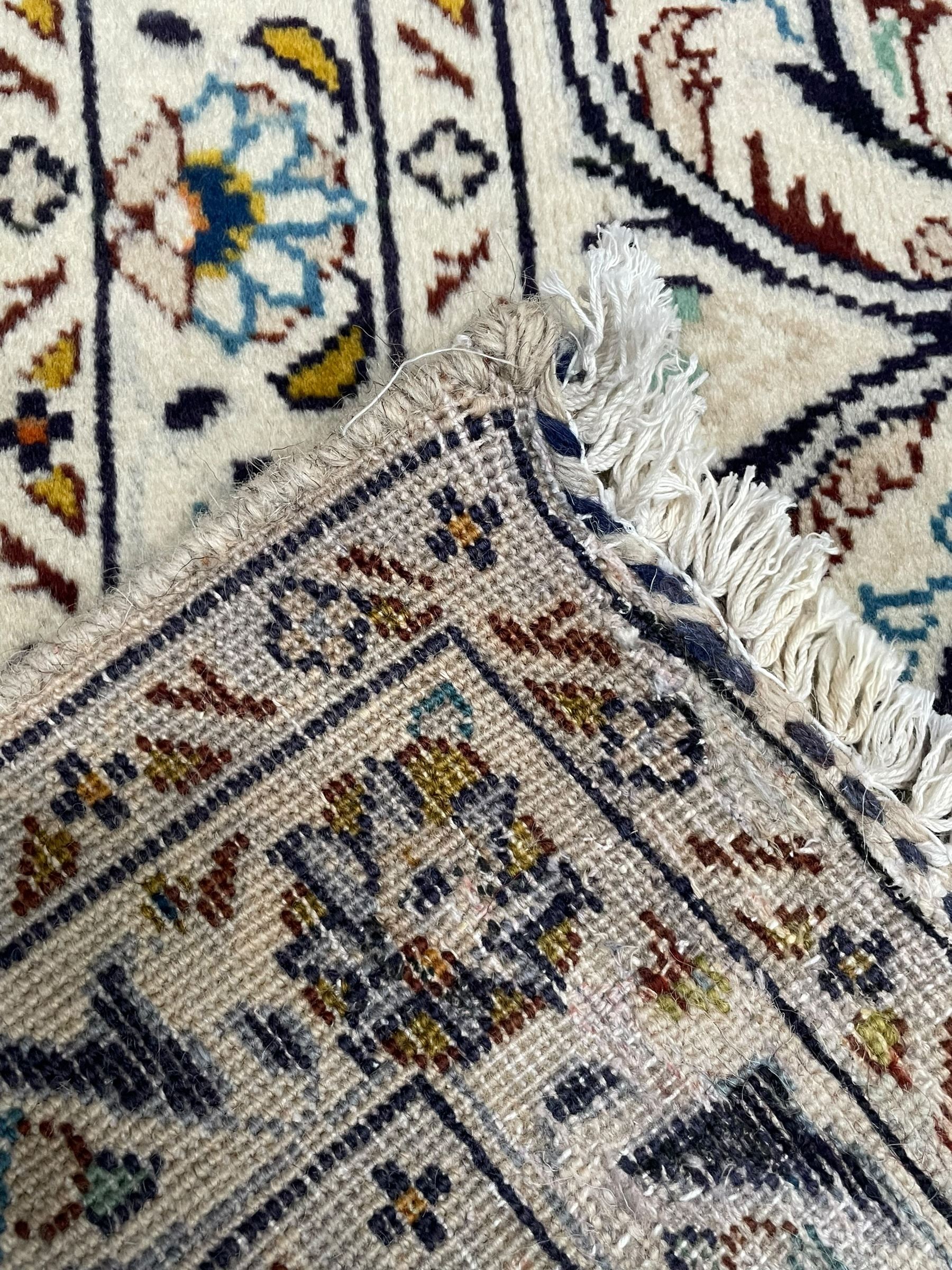 Persian Kashan ivory ground carpet, central pole medallion surrounded by swirling leafy branches and stylised plant motifs, scrolled foliate spandrels, the main border decorated with scrolling pattern and repeating palmettes, within floral patter guard stripes 