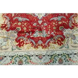 Persian silk inlaid crimson ground Kashan rug, the central shaped field with a floral pole medallion surrounded by trailing floral motifs and festoons of flowerheads, the wide cyan guard line with repeating palmettes and scrolling floral vines